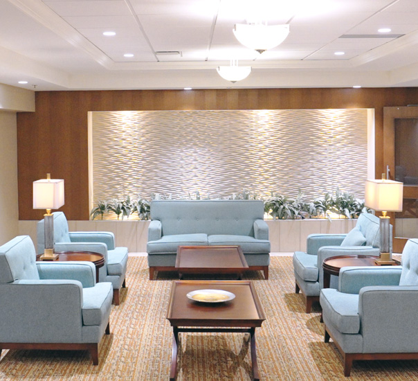 Lobby lounge with light blue sofas and armchairs around wood coffee tables on a patterned rug.