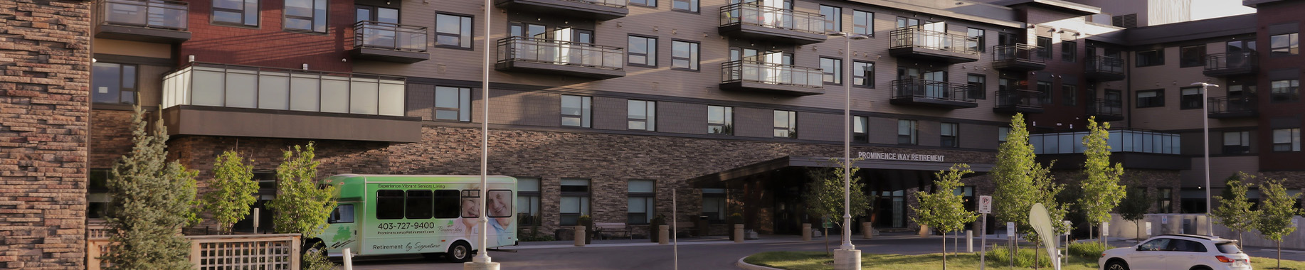 Prominence Way Retirement building exterior with a green shuttle bus parked in front.