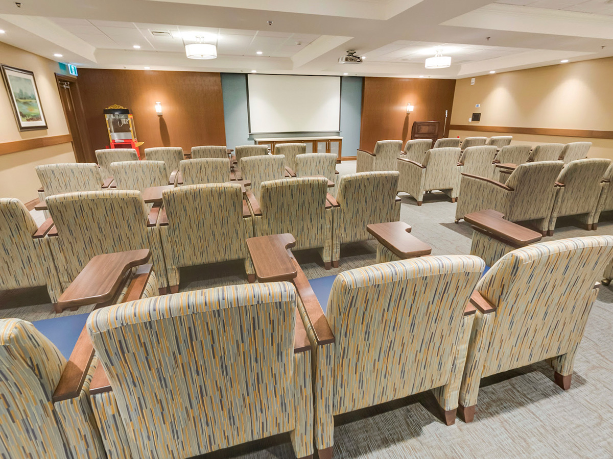 Retirement community theatre with rows of seats, a projection screen and a popcorn machine.