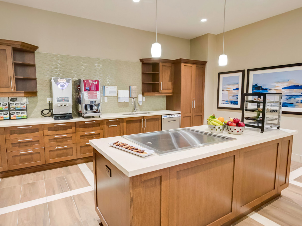 Kitchen island with fruit and snacks in front, coffee station and artwork along the counter behind.